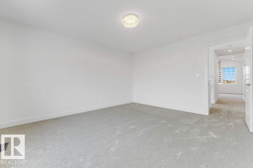 Neutral-toned carpeting and white walls characterize this room, illuminated by a contemporary flush-mount ceiling fixture - 7403 Singer Landing Landing, Edmonton, AB - Indoor Photo Showing Other Room