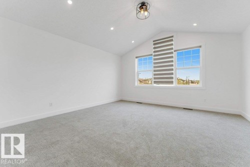 Spacious room featuring vaulted ceilings, recessed lighting, and a modern semi-flush mount fixture - 7403 Singer Landing Landing, Edmonton, AB - Indoor Photo Showing Other Room