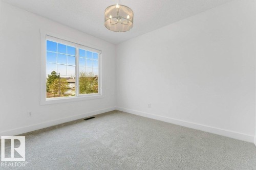 Bright room with a large window featuring white grid panes and trim - 7403 Singer Landing Landing, Edmonton, AB - Indoor Photo Showing Other Room