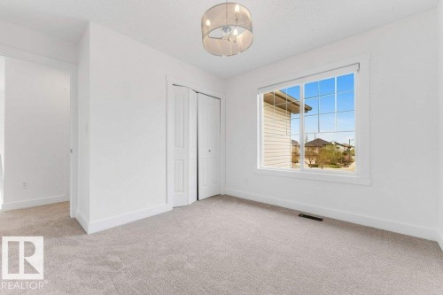 Bright interior room featuring a large window with grid panes, white trim, and a contemporary semi-flush mount light fixture - 7403 Singer Landing Landing, Edmonton, AB - Indoor Photo Showing Other Room