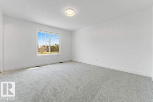 Spacious room featuring light gray carpet, white walls, and a large multi-pane window with white trim - 7403 Singer Landing Landing, Edmonton, AB - Indoor Photo Showing Other Room