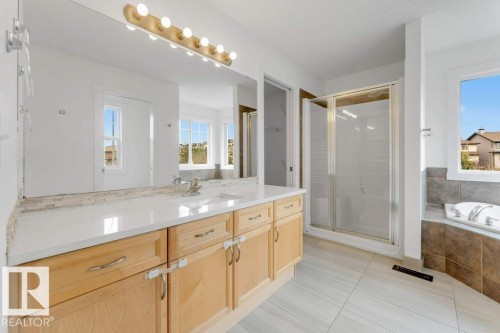 Dual vanity with white countertop, integrated sinks, and natural wood cabinetry - 7403 Singer Landing Landing, Edmonton, AB - Indoor Photo Showing Bathroom