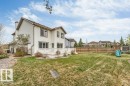 Expansive rear yard featuring a large composite deck with white railings, a wooden privacy fence, mature trees, and a two-story home with white siding - 7403 Singer Landing Landing, Edmonton, AB  - Outdoor 
