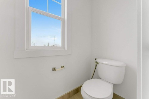 White trim window with clear glass, white walls, light wood-finish flooring, and a white toilet - 7403 Singer Landing Landing, Edmonton, AB - Indoor Photo Showing Bathroom