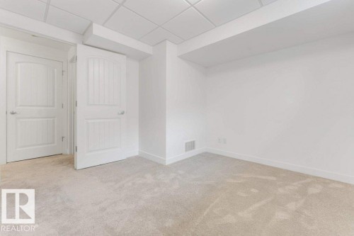 Neutral-toned carpet flooring with white baseboards and two arched panel doors - 7403 Singer Landing Landing, Edmonton, AB - Indoor Photo Showing Other Room