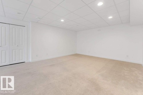 Spacious room featuring neutral carpeting, white walls, and a grid drop ceiling with recessed lighting - 7403 Singer Landing Landing, Edmonton, AB - Indoor Photo Showing Other Room
