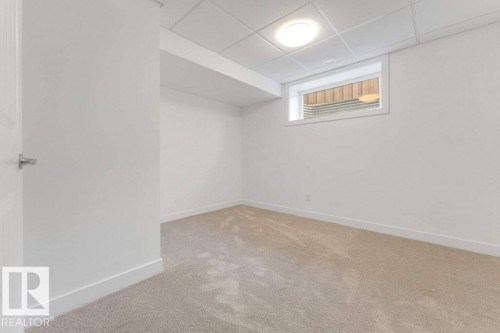 Carpeted room featuring a drop ceiling with recessed lighting, an egress window, and white trim - 7403 Singer Landing Landing, Edmonton, AB - Indoor Photo Showing Other Room