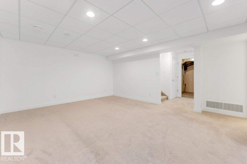 Spacious room featuring neutral carpeting, white walls, recessed lighting, drop ceiling, and a visible air return vent - 7403 Singer Landing Landing, Edmonton, AB - Indoor Photo Showing Other Room