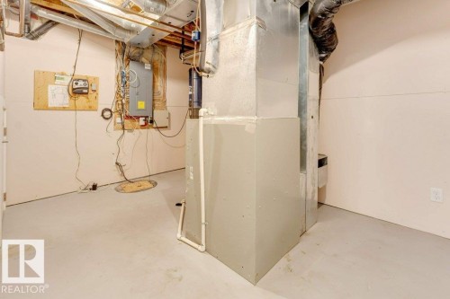 Basement utility area featuring exposed overhead ductwork, a large floor-standing furnace, a floor drain, and electrical paneling - 7403 Singer Landing Landing, Edmonton, AB - Indoor Photo Showing Basement