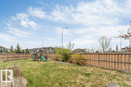 Expansive backyard featuring a full perimeter wood fence, mature landscaping, and a green lawn area - 7403 Singer Landing Landing, Edmonton, AB - Outdoor