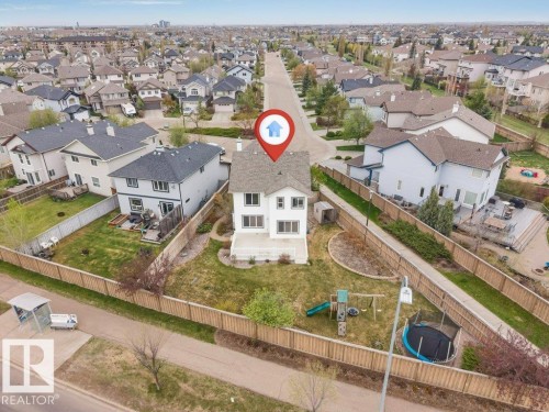 Two-story residence with a white exterior and a gabled roof, featuring a rear deck, a fenced backyard, and established landscaping - 7403 Singer Landing Landing, Edmonton, AB - Outdoor With View