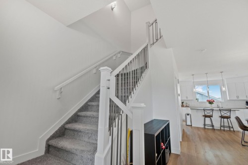Carpeted staircase with white balusters and dark metal spindles - 21027 130 Avenue, Edmonton, AB - Indoor Photo Showing Other Room