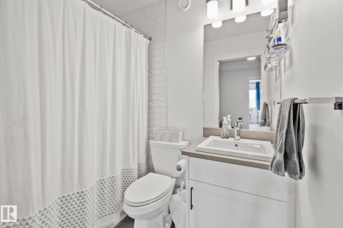 Contemporary bathroom featuring a white vanity with a rectangular sink, a light-toned countertop, and a large wall mirror - 21027 130 Avenue, Edmonton, AB - Indoor Photo Showing Bathroom