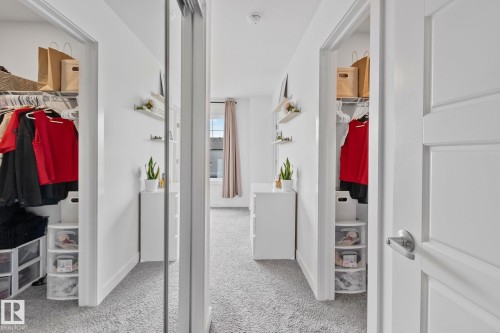 Carpeted room with a sliding mirrored closet door, a paneled interior door, and a built-in closet system - 21027 130 Avenue, Edmonton, AB - Indoor Photo Showing Other Room