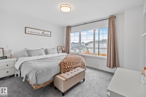 Bright bedroom featuring a large multi-pane window, flush-mount ceiling light, and carpeted flooring - 21027 130 Avenue, Edmonton, AB - Indoor Photo Showing Bedroom