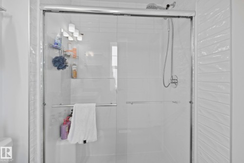 Enclosed shower with sliding glass doors and a chrome handheld shower fixture - 21027 130 Avenue, Edmonton, AB - Indoor Photo Showing Bathroom