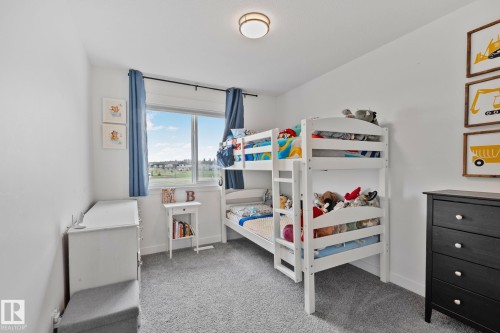 Bright room featuring a wide window with blue drapes, white walls, and light gray carpet flooring - 21027 130 Avenue, Edmonton, AB - Indoor Photo Showing Bedroom