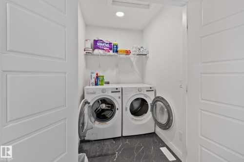 Dedicated laundry area featuring a front-load washer and dryer, wire shelving, recessed lighting, and dark marble-look flooring - 21027 130 Avenue, Edmonton, AB - Indoor Photo Showing Laundry Room