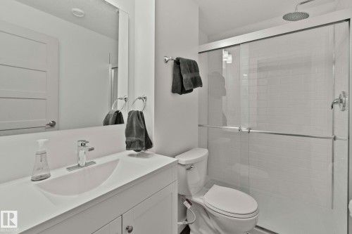 Bathroom featuring a white vanity with an integrated sink, chrome faucet, and a large mirror - 21027 130 Avenue, Edmonton, AB - Indoor Photo Showing Bathroom