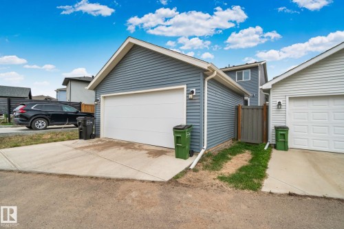 Detached garage featuring blue horizontal siding, a white garage door, and a concrete driveway - 21027 130 Avenue, Edmonton, AB - Outdoor
