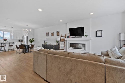 Spacious living area featuring light wood-finish flooring, recessed lighting, and a contemporary fireplace with a white mantel - 21027 130 Avenue, Edmonton, AB - Indoor Photo Showing Living Room With Fireplace