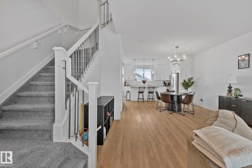 Open-concept living area featuring light wood-finish flooring throughout, a modern chandelier, and recessed lighting - 21027 130 Avenue, Edmonton, AB - Indoor