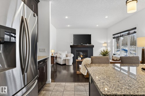 The kitchen features a stainless steel refrigerator and granite countertops - 26 Edgewater Terr N, St. Albert, AB - Indoor With Fireplace