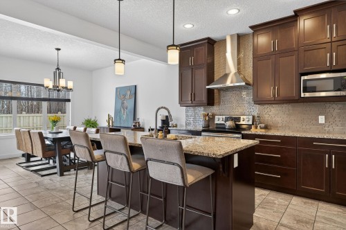 The kitchen features rich wood cabinetry, stainless steel appliances, and granite countertops - 26 Edgewater Terr N, St. Albert, AB - Indoor Photo Showing Kitchen With Upgraded Kitchen