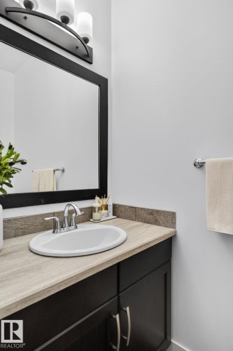 Bathroom vanity with a dark wood cabinet, a light-colored countertop, and a white oval sink with a chrome faucet - 26 Edgewater Terr N, St. Albert, AB - Indoor Photo Showing Bathroom