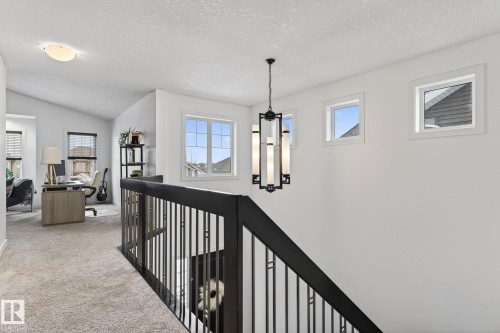 Loft area with carpeted flooring, a contemporary black metal baluster railing, and a modern chandelier - 26 Edgewater Terr N, St. Albert, AB - Indoor Photo Showing Other Room