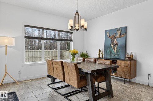 Dining area featuring tiled flooring, a decorative chandelier, and a large window providing natural light - 26 Edgewater Terr N, St. Albert, AB - Indoor