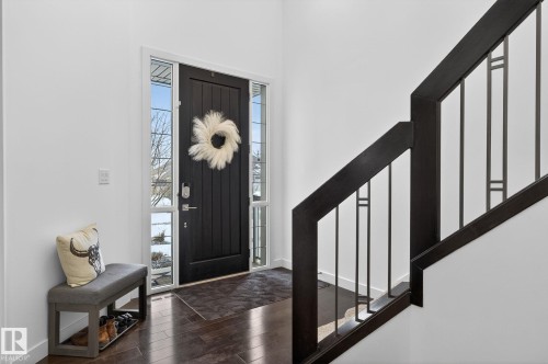 The property features a dark wood front door with sidelight windows, dark wood flooring, and a staircase with contemporary dark wood and metal railings - 26 Edgewater Terr N, St. Albert, AB - Indoor Photo Showing Other Room