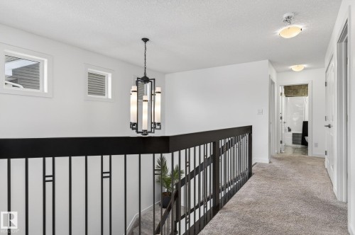 Upper level landing featuring a modern chandelier, two windows, and a carpeted hallway - 26 Edgewater Terr N, St. Albert, AB - Indoor Photo Showing Other Room