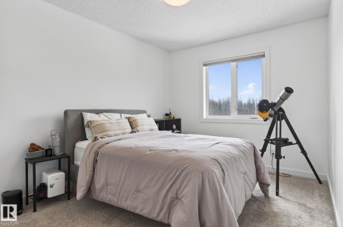 This room features a window with views of mature trees, light-colored walls, and carpeting - 26 Edgewater Terr N, St. Albert, AB - Indoor Photo Showing Bedroom