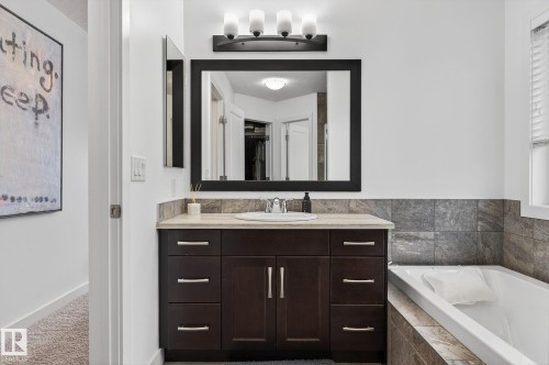 Bathroom featuring a dark wood vanity with a light-colored countertop, an undermount sink, and a framed mirror - 26 Edgewater Terr N, St. Albert, AB - Indoor Photo Showing Bathroom