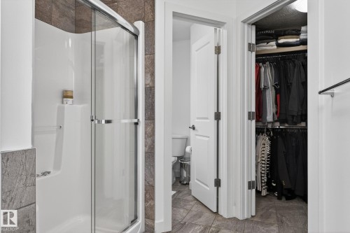 Bathroom featuring a shower with glass enclosure and tiled walls, a toilet, and a closet with clothing racks - 26 Edgewater Terr N, St. Albert, AB - Indoor Photo Showing Bathroom