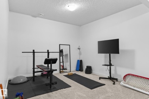 The property features a dedicated fitness area with carpeted flooring and white walls, offering a versatile space for exercise - 26 Edgewater Terr N, St. Albert, AB - Indoor Photo Showing Gym Room