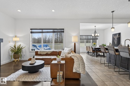 This living space features dark hardwood flooring, recessed lighting, and a large window providing views of the outdoors - 26 Edgewater Terr N, St. Albert, AB - Indoor Photo Showing Living Room With Fireplace