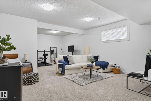 This spacious living area features light gray carpeting, recessed lighting, and a window with blinds - 26 Edgewater Terr N, St. Albert, AB - Indoor