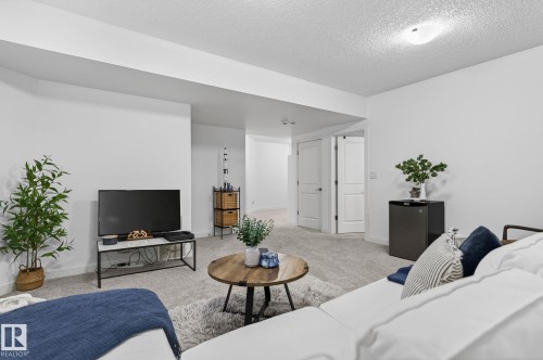 This living area features light-colored carpeting, white walls, and recessed lighting, creating a bright and inviting atmosphere - 26 Edgewater Terr N, St. Albert, AB - Indoor