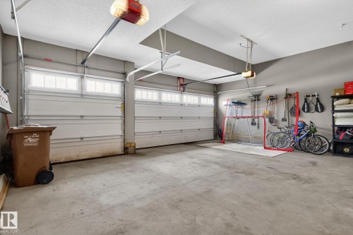 The property features an attached garage with concrete flooring, two garage doors with windows, and two garage door openers - 26 Edgewater Terr N, St. Albert, AB - Indoor Photo Showing Garage