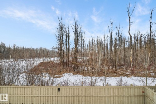 The property features a private fenced yard with a view of a wooded area and snow-covered ground - 26 Edgewater Terr N, St. Albert, AB - Outdoor With View