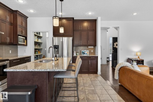 The kitchen features dark wood cabinetry, granite countertops, and stainless steel appliances - 26 Edgewater Terr N, St. Albert, AB - Indoor Photo Showing Kitchen With Upgraded Kitchen