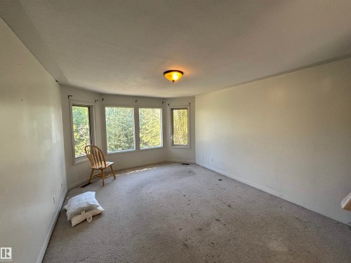 Spacious room featuring a bay window with multiple panes, ceiling-mounted light fixture, and wall-to-wall carpeting - 3516 49 Avenue, Drayton Valley, AB - Indoor Photo Showing Other Room