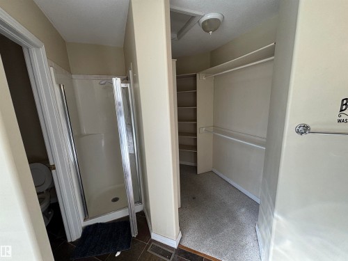 Walk-in closet featuring built-in shelving, hanging rods, and a flush-mount light fixture - 3516 49 Avenue, Drayton Valley, AB - Indoor