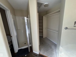 Walk-in closet featuring built-in shelving, hanging rods, and a flush-mount light fixture - 