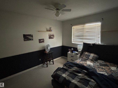 Room featuring a ceiling fan with light fixture, window with horizontal blinds, two-tone wall treatment, and light-colored carpeting - 3516 49 Avenue, Drayton Valley, AB - Indoor Photo Showing Bedroom
