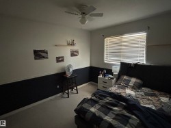 Room featuring a ceiling fan with light fixture, window with horizontal blinds, two-tone wall treatment, and light-colored carpeting - 