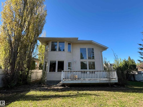 Rear exterior featuring a spacious wooden deck with railings, stucco siding, and multiple large windows across two levels - 3516 49 Avenue, Drayton Valley, AB - Outdoor With Deck Patio Veranda