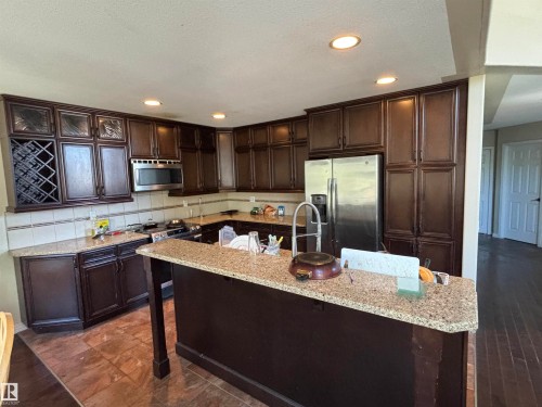 Kitchen featuring dark wood cabinetry, granite countertops, and stainless steel appliances - 3516 49 Avenue, Drayton Valley, AB - Indoor Photo Showing Kitchen With Upgraded Kitchen